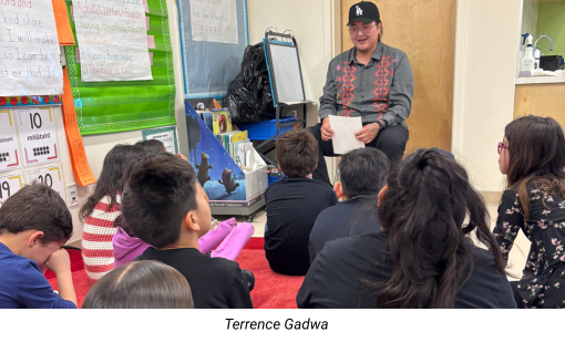 Terrence Gadwa sitting with a group of students on the floor of a classroom