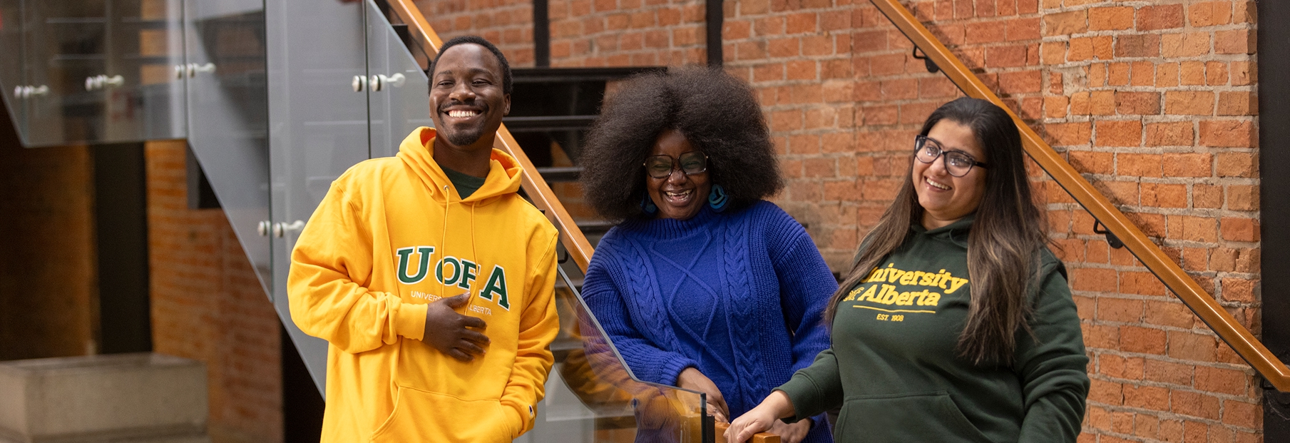 Three University of Alberta students posing together in an indoor campus space.