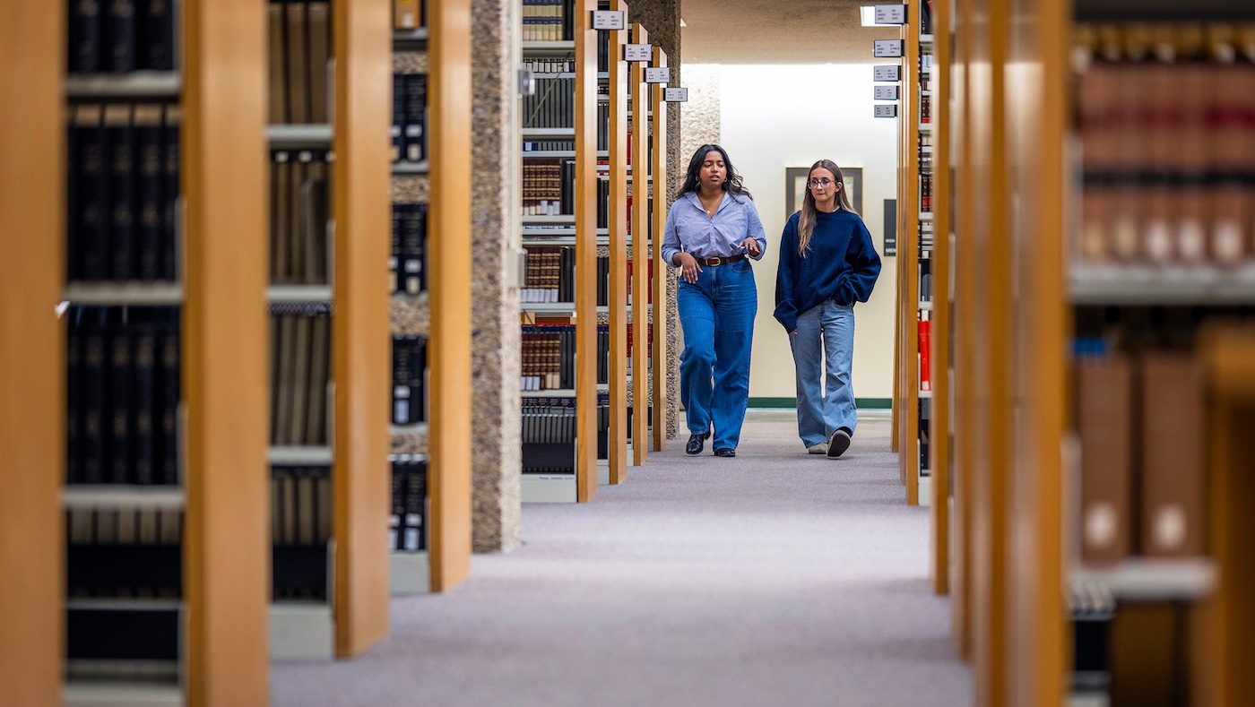 Maria Kalapurayil and Helena Rizzuto walk down the aisles of the law library