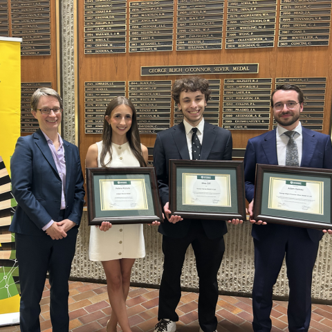 The faculty's 3 medallists pose with their plaques beside Dean Fiona Kelly