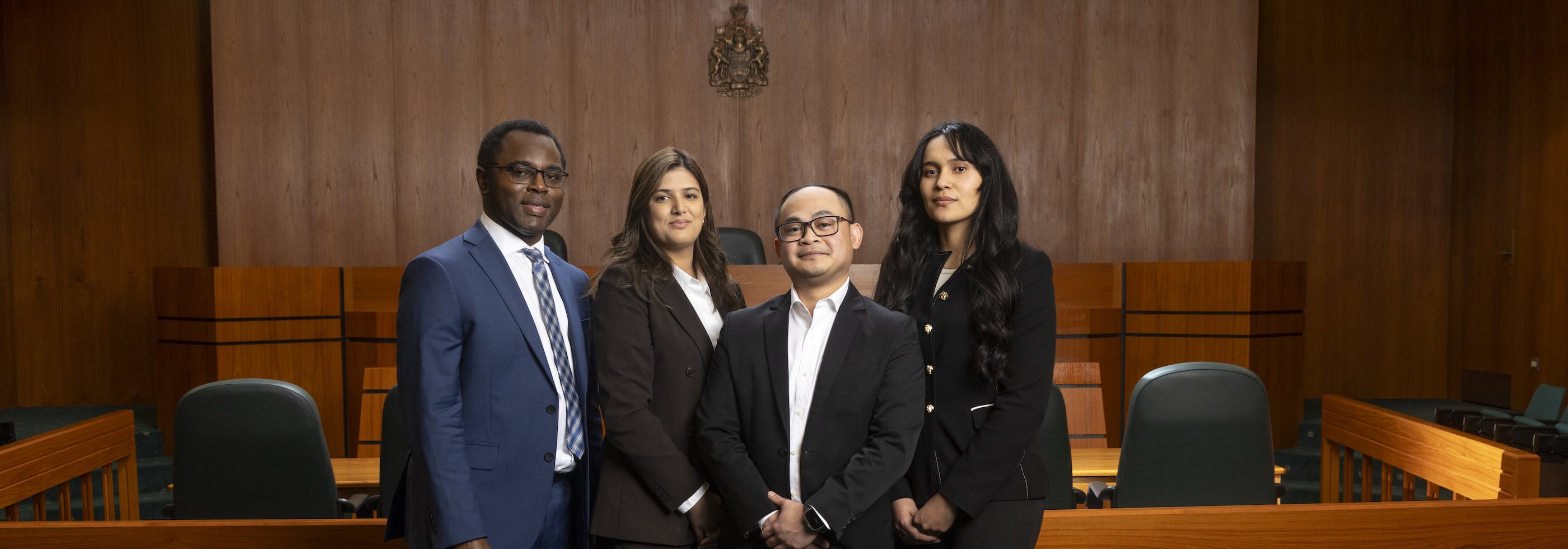 4 students standing proudly in the moot courtroom