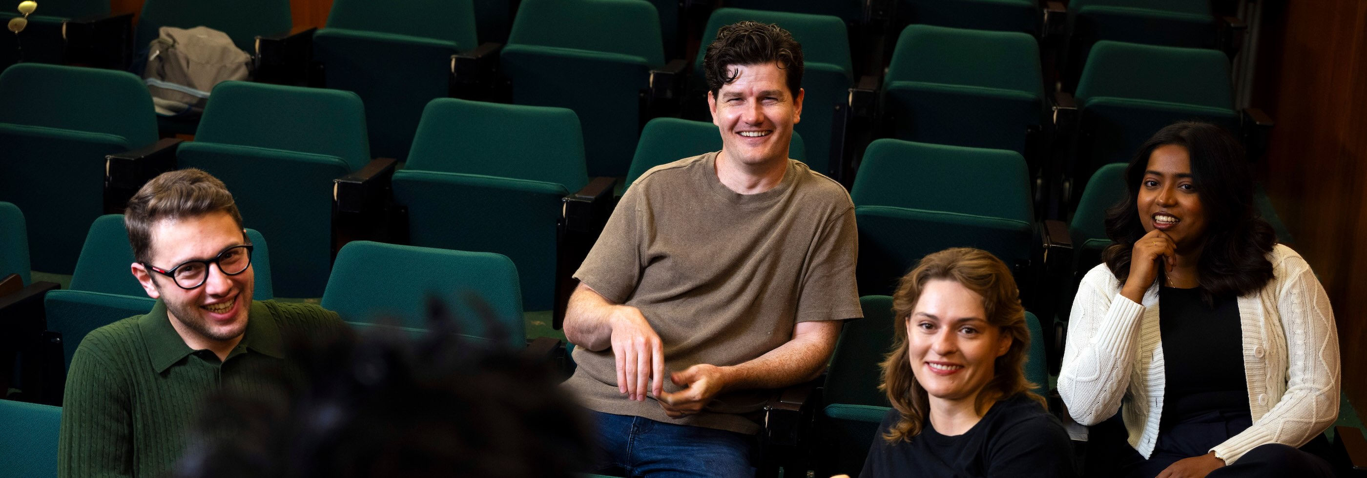 A small group of students listening to a presenter in an auditorium