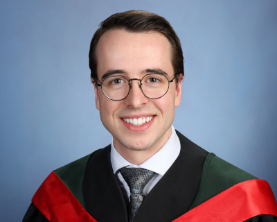 A studio portrait shows a student smiling at the camera in a black graduation gown