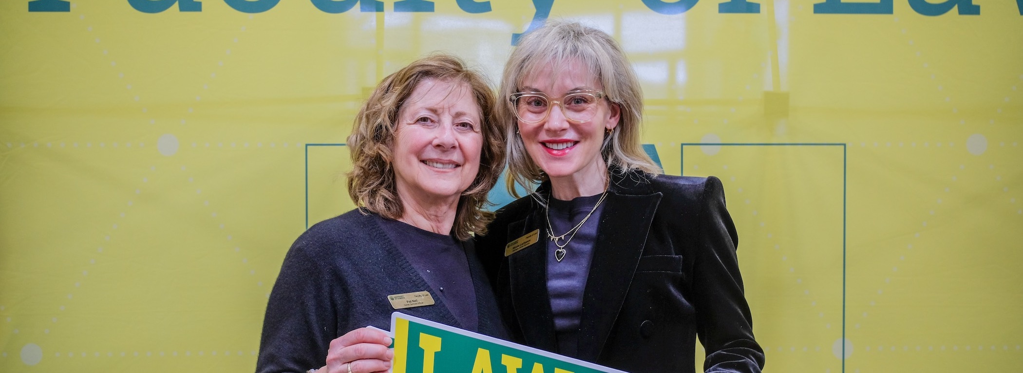 Pat Neil and Nicole Lachance holding a Law pennant banner