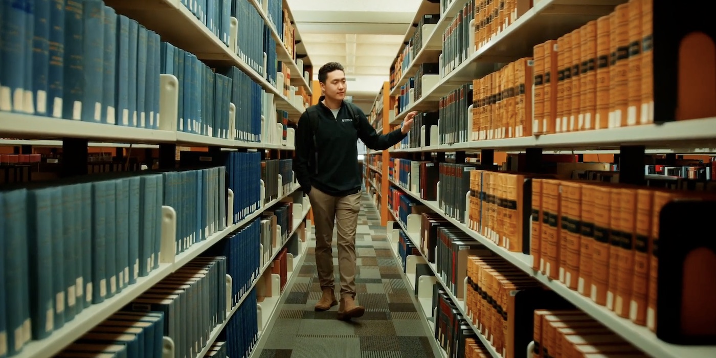 Man walks down the aisles of the Weir Law Library