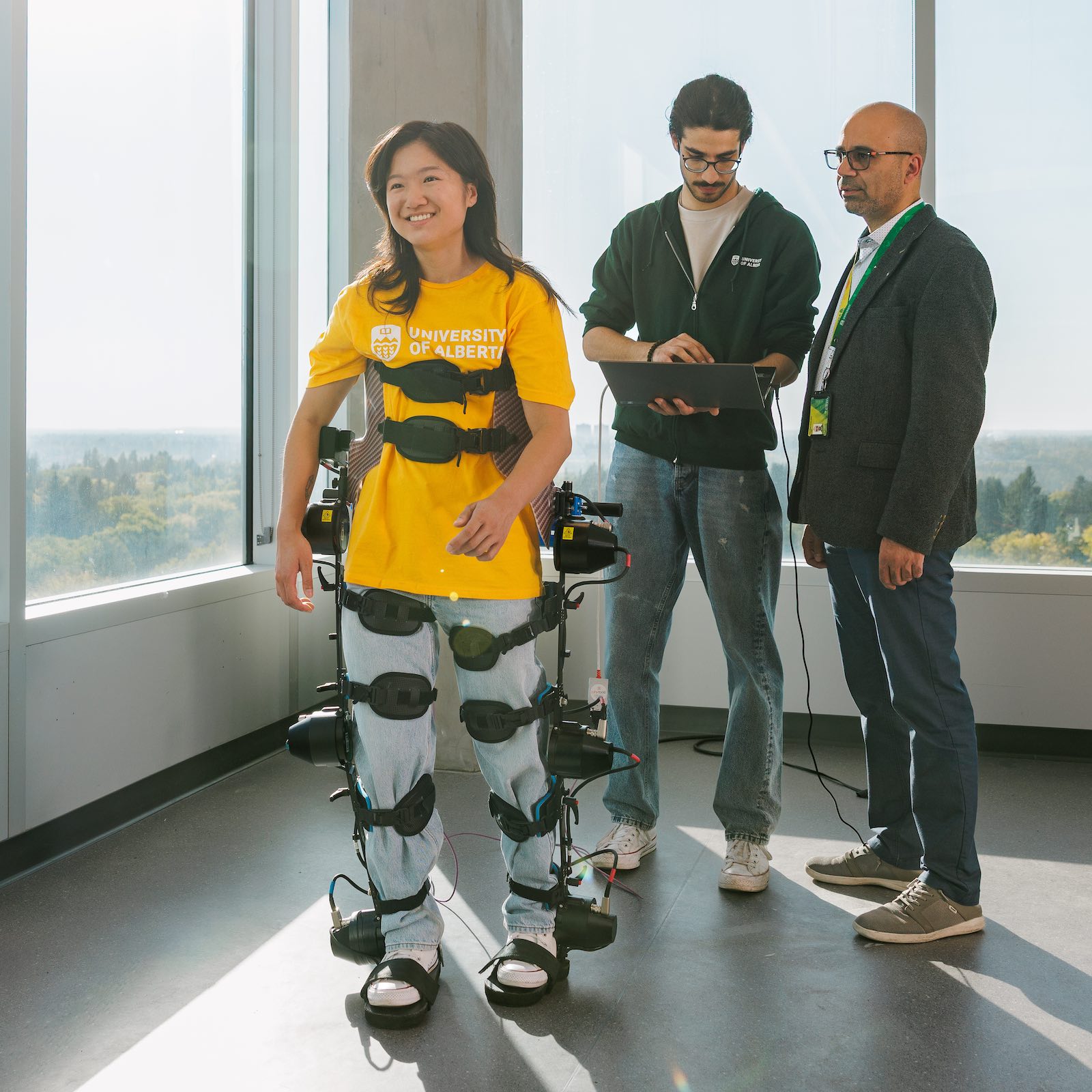 Two researchers from the Telerobotic and Biorobotic Systems Group monitor a woman walking with assistance from robotic components