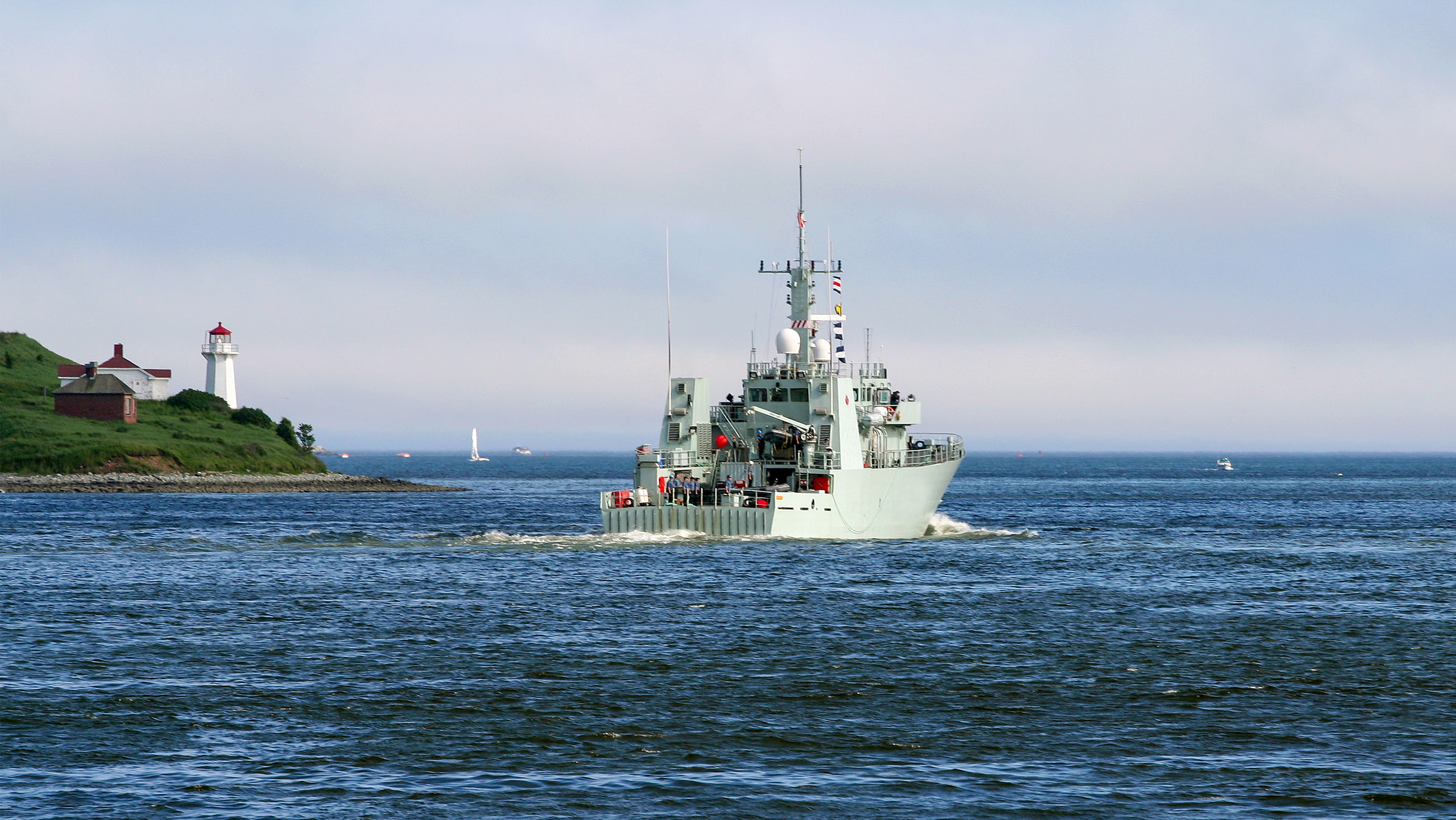 Photo of a navy ship in the ocean by the coast